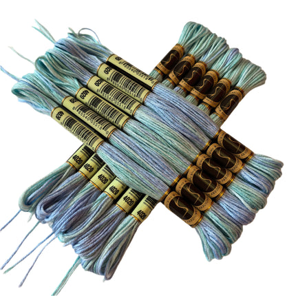 Bundles of embroidery thread in light blue and gray on a beige background