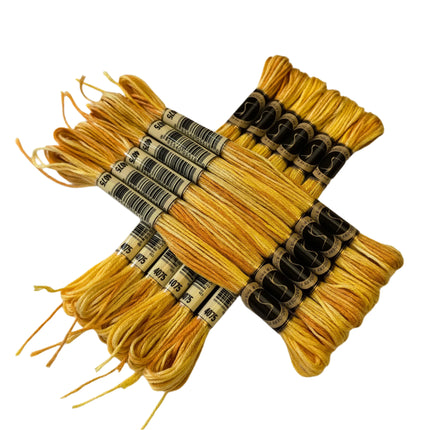 Yellow embroidery floss skeins with labels on a beige fabric background