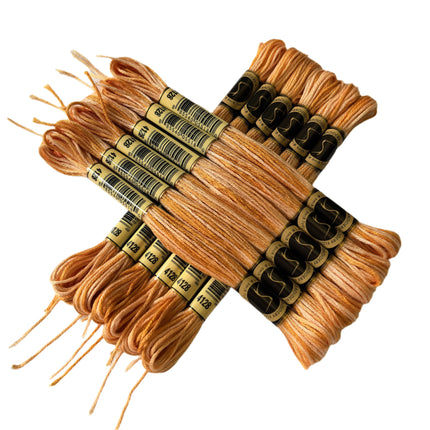Set of beige embroidery floss with labels on a light fabric background