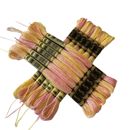 Set of pink and yellow embroidery threads on a light background