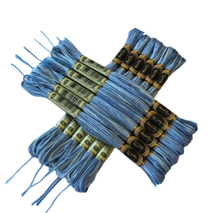 Blue embroidery floss with gold spools on a beige fabric background